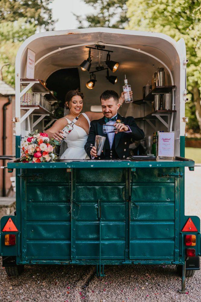 couple celebrating their wedding mixing a cocktail in front of Ballogie House, Aberdeenshire