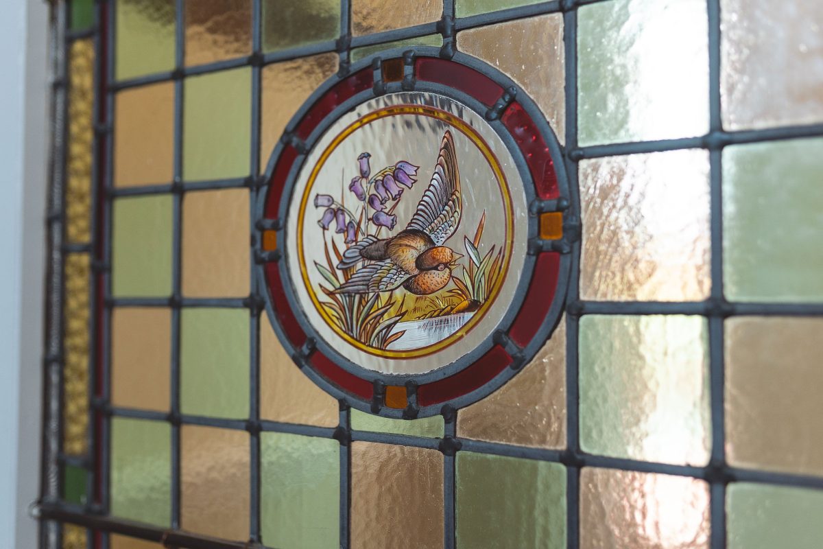 Potarch Lodge detail shot of the stained glass found in the porch area, featuring a bird and bluebells